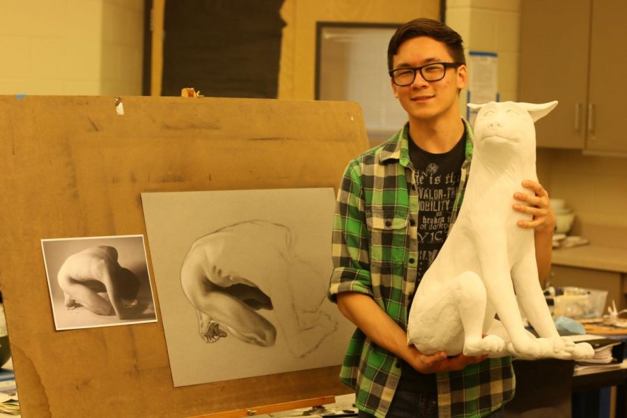Tyler Quintin poses with new art pieces for his gallery exhibition. He sculpted a ceramic wolf for his series of animal pieces and began sketching a nude figure.