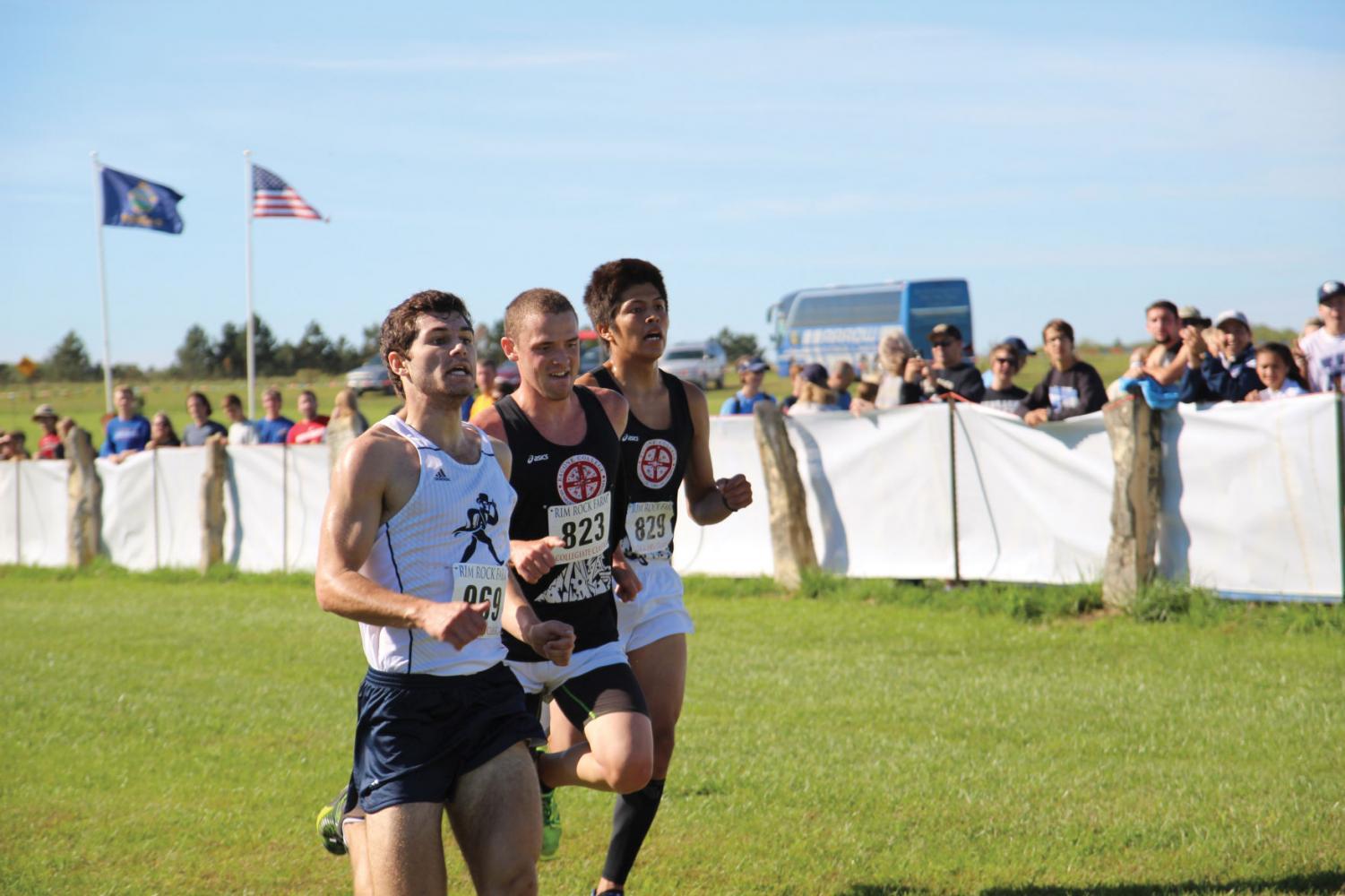 Derek Meeks passes two runners as he sprints through the finish line chute to end his eight kilometer race.