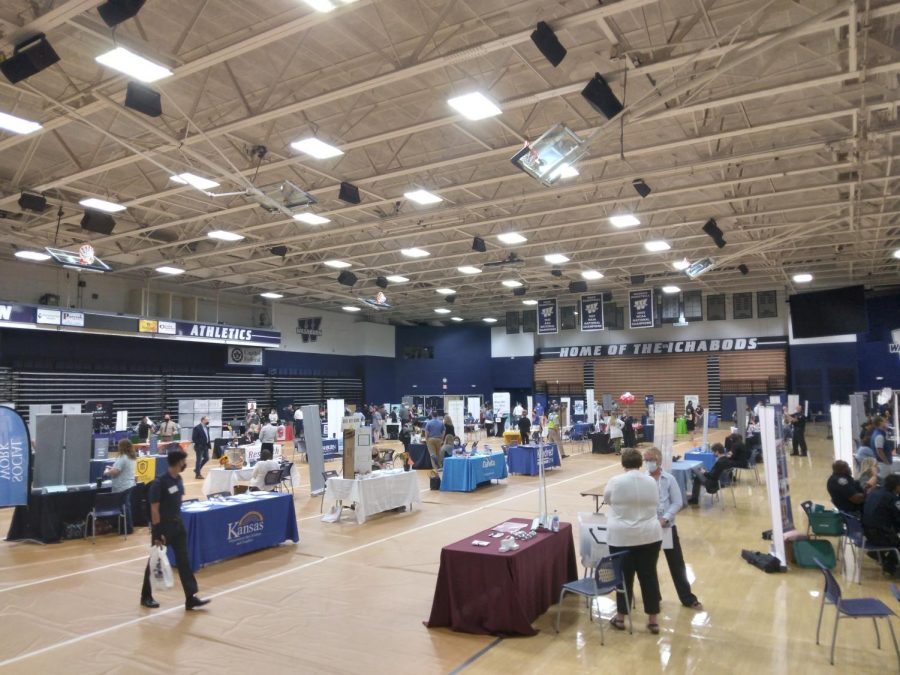The fleet of tables: A student walks with a bag of items while looking at surrounding tables. The Career and Grad School Fair was held Wednesday, Sept. 15 in Lee Arena.