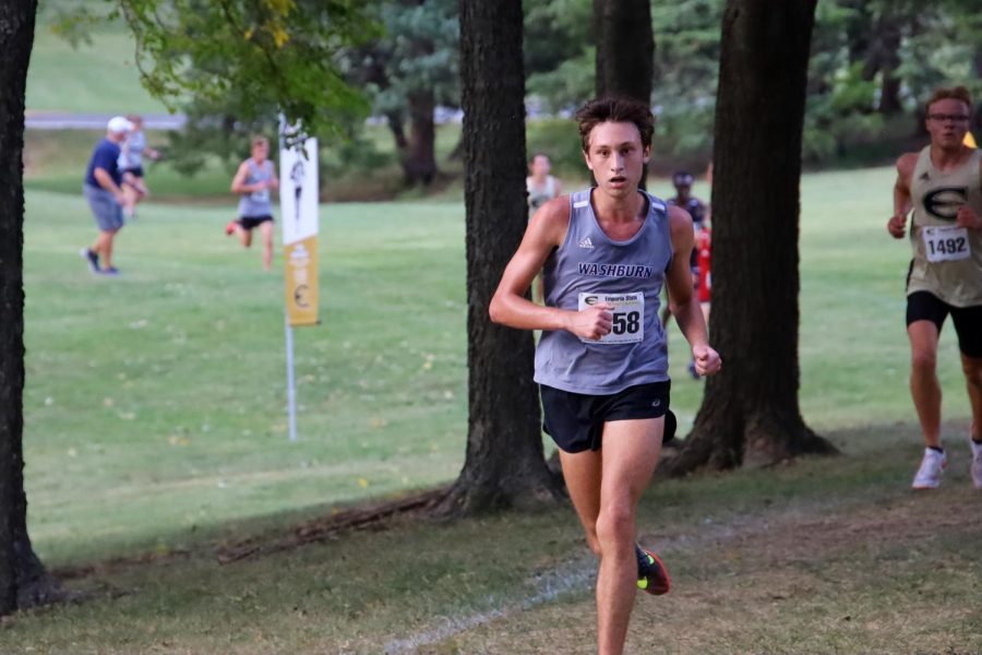 Through the woods: Cooper Griffin runs ahead of an Emporia competitor through the wooded portion of the course. Cooper finished 37th, earning 31 points for the team.