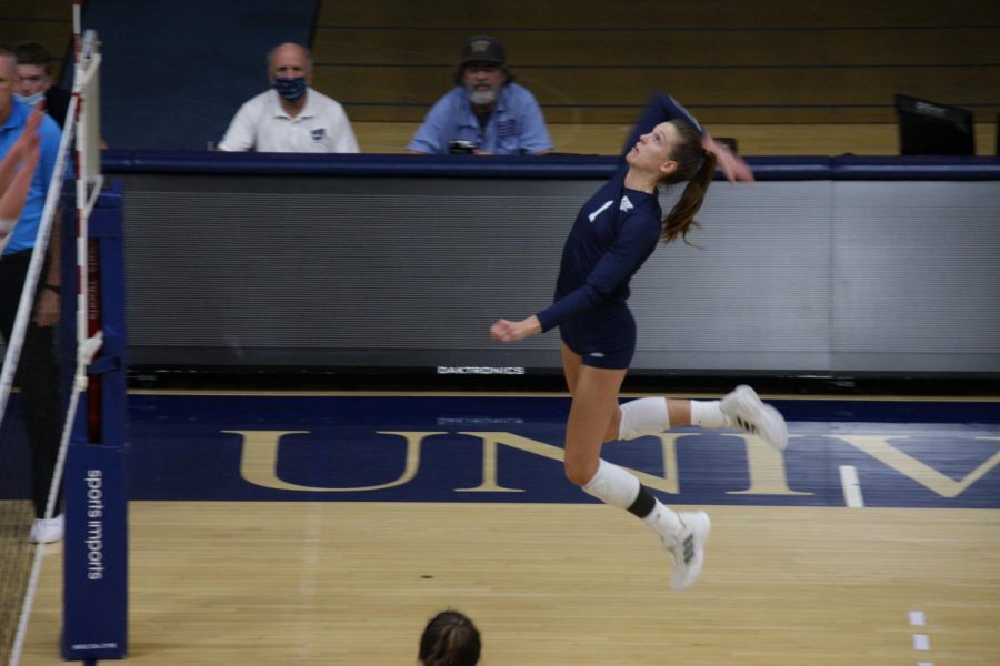 Floating: Senior outside hitter Genna Berg leaps to attack a ball on the outside net on Oct. 1, 2021. Berg finished the match with 7 kills and 3 blocks.