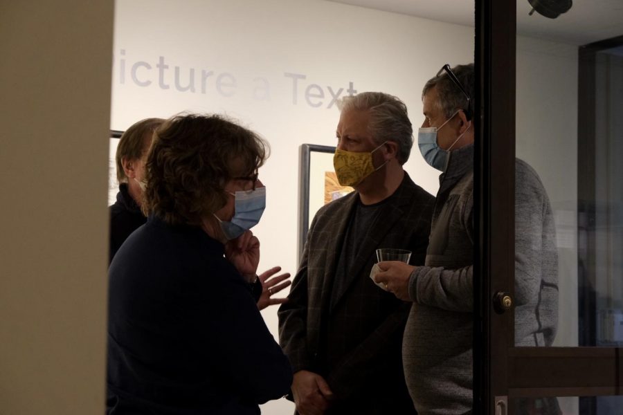 Discussions: Stephen Johnson (yellow face mask) talks to attendees about his Art on Nov. 5, 2021. The event was held at Mulvane Art Museum.