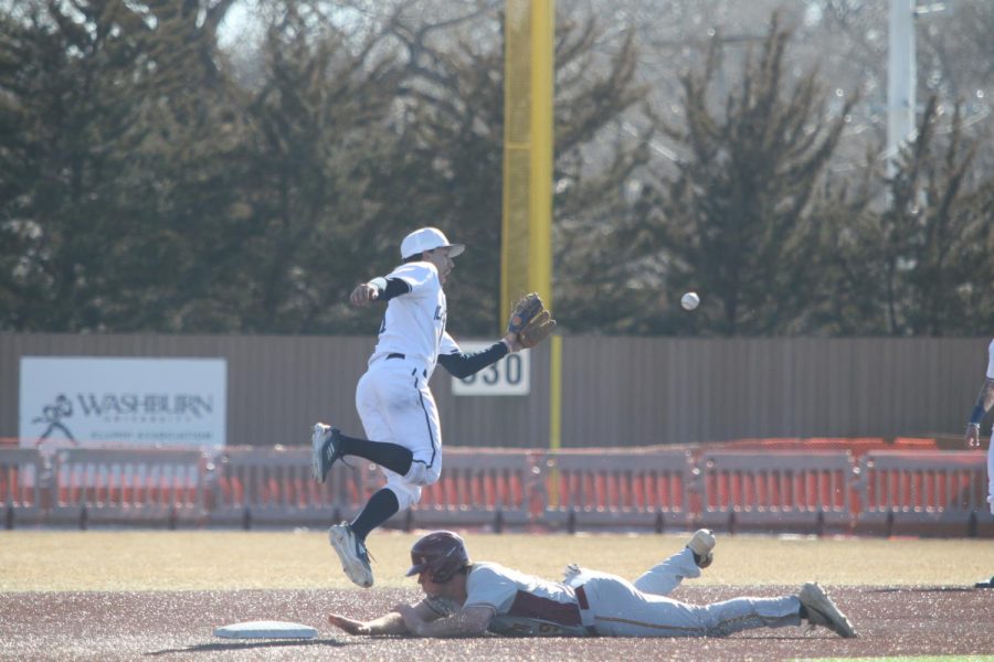 Junior Cal Watkins jumps to catch a throw while avoiding the baserunner Feb. 20, 2022. Watkins scored one run in the first game of the day.