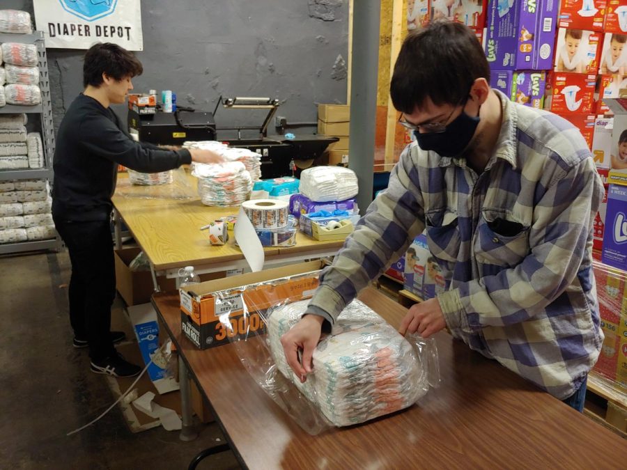 Shota Nagino (left), senior sociology major, and Jackson Woods (right), senior sociology major, volunteer their time to repackage bundles of diapers together at Community Action. Repackaged diapers are given to families in need every month.