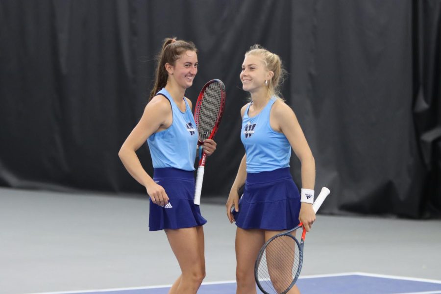 Senior Kinsey Fields (left) and sophomore Maja Jung (right) smile after winning a point April 23, 2022. Washburn defeated Northeastern State 7-0 in the match.