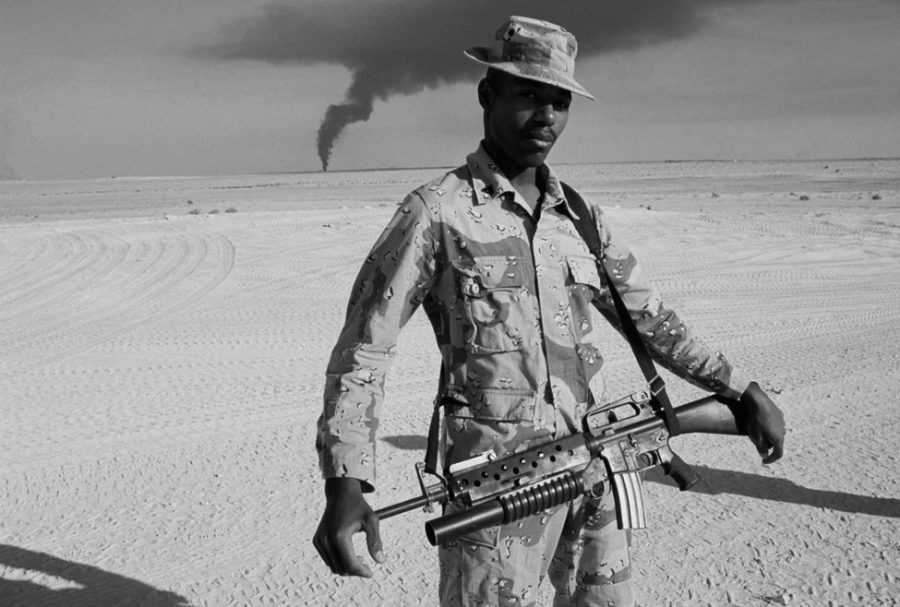 A soldier appears to guard something burning the distance in this photograph, taken by Peter Turnley, currently on display in Mulvanes Truth exhibit. Turnley captured this image during the Gulf War. Peter Turnley, Gulf War, Kuwait, 1991, archival pigment print, Mulvane Art Museum Permanent Collection.