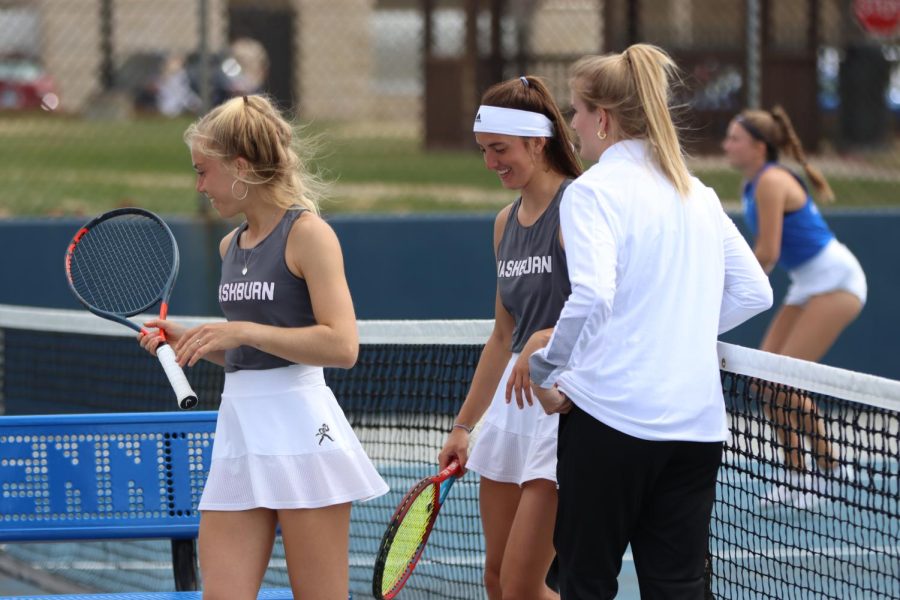 Sophomore Maja Jung (left) and junior Kinsey Fields (middle) smile and talk to graduate assistant Logan Morrissey (right) after a game March 29, 2022. Jung and Fields won their No. 2 doubles match 6-0.