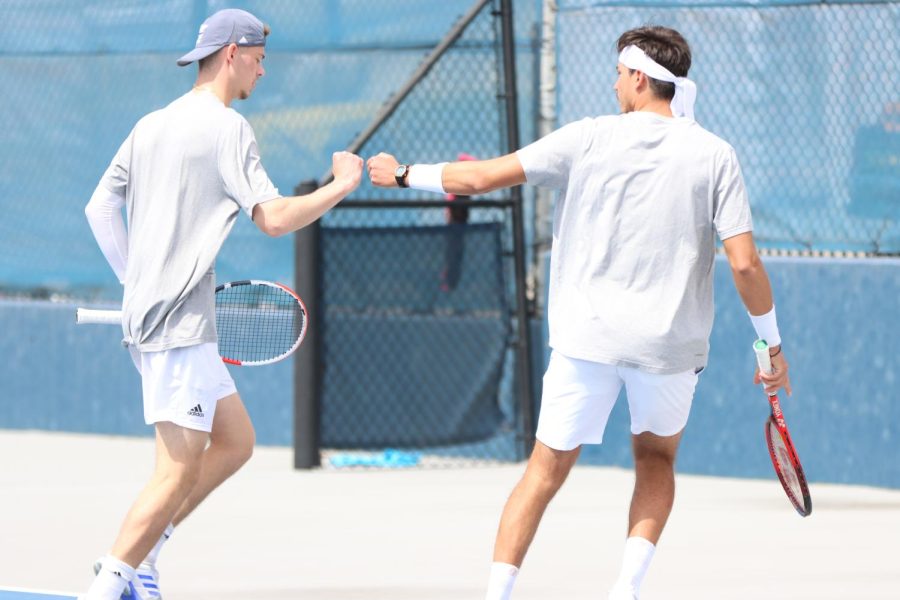 Freshman Noah Neideck (left) and senior Raul-Alin Dicu fist bump after a point March 29, 2022. Neideck and Dicu lost their No. 2 doubles match 6-3.