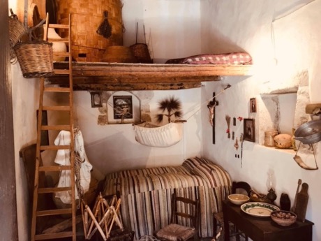 A cradle hangs in the corner amid a Catholic crucifix and blessed palm leaves. This typical Sicilian residence at the turn of the 20th century is one of the many places Kerry Wynn visited in 2019.