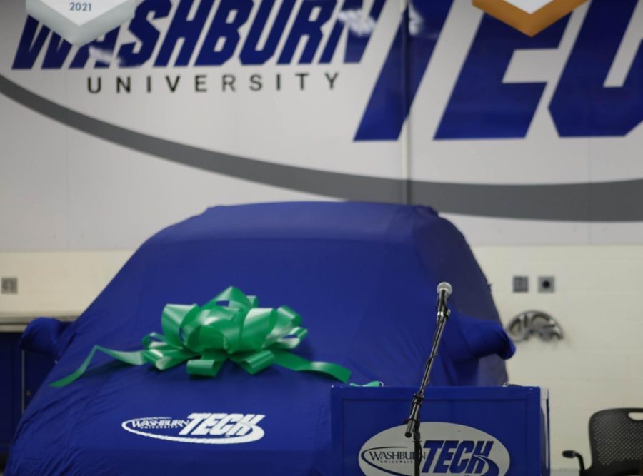 The minivan sits underneath cloth and a ribbon for the grand unveiling. The 2007 Chrysler Town & Country marks the 33rd car donated by Washburn Tech through the Recycled Rides program.