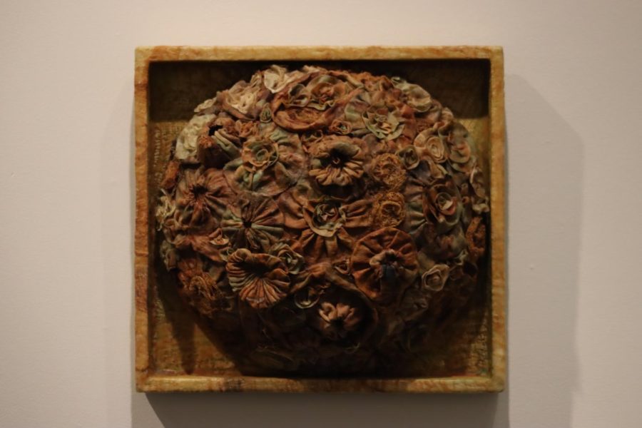 “Primordial (2020)” by Leandra Spangler hangs on the wall. It was made with encaustic paint and rust-dyed cotton cloth.