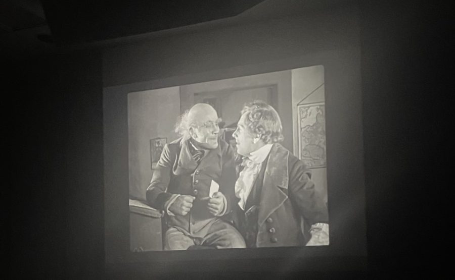 Krock, the estate agent and servant of the vampire Orlock, speaks with Hutter during the film Nosferatu.