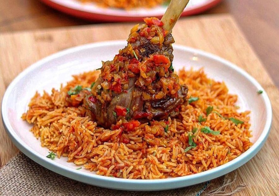 To make jollof rice, blend tomatoes, pepper and other ingredients. Jollof rice is served on a plate with chicken dipped in tomato and pepper mix, with a sprinkling of shredded parsley leaves. 