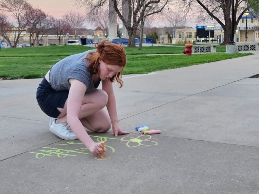 Chloe Chaffin, president of URGE, draws flowers outside of the Memorial Union to show support for the transgender community. Chaffins final message read let trans joy grow.