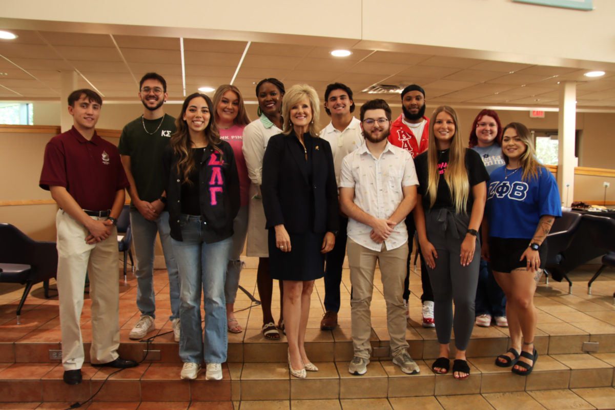 President JuliAnn Mazachek poses with the members of the Fraternity and Sorority Life to reveal their banners in the Union Café on Aug. 29. She was excited to see the banners and to help get the fraternities and sororities noticed on campus to incoming students.