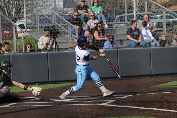 Madi Moore, freshman catcher, takes a swing at the ball. The hit made it through the infield and Moore secured a single in game one of the series. 