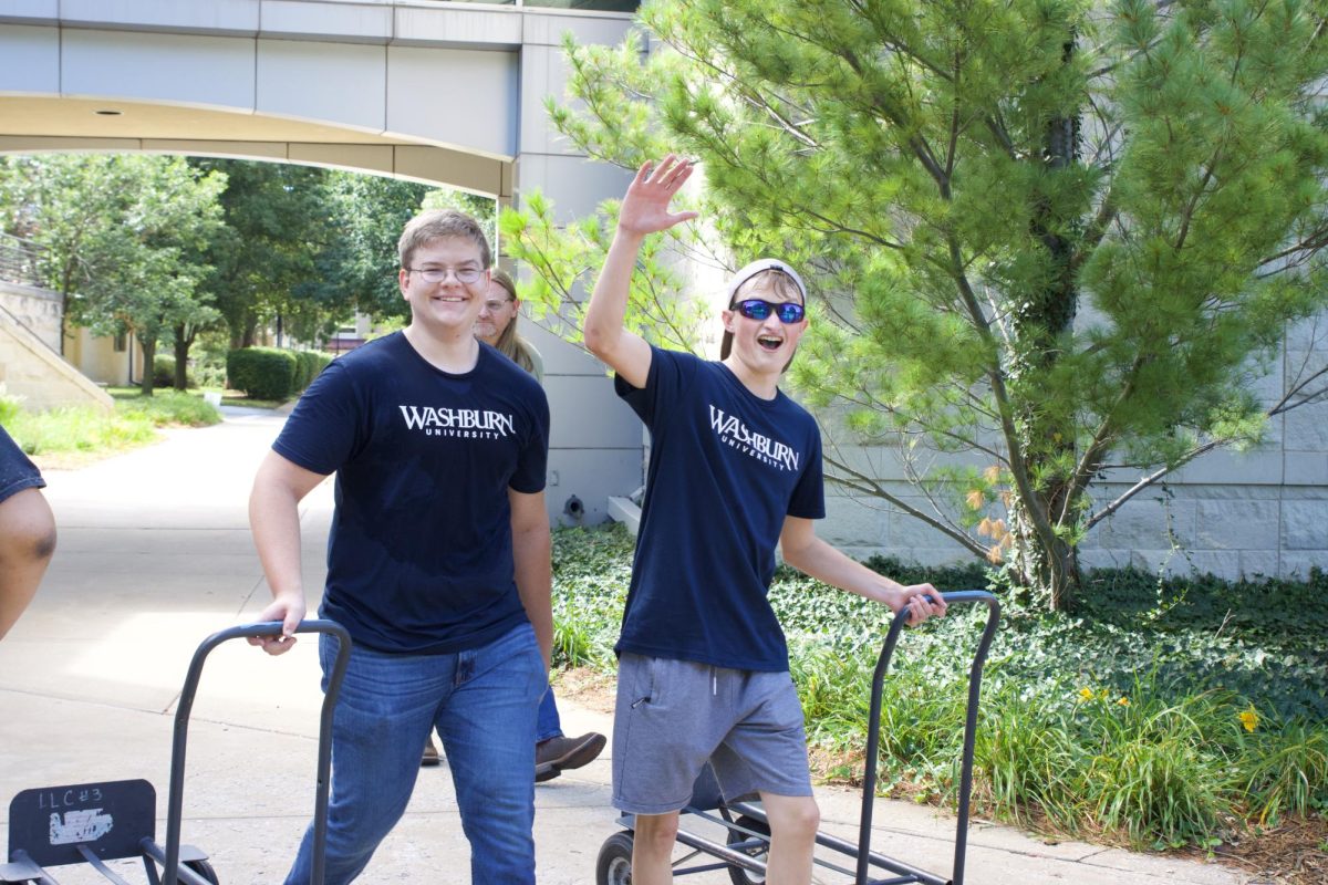 Johan Campbell (left), sophomore nursing student, and Sam Revell (right), junior kinesiology major, say hello to incoming students. Campbell and Revell were both volunteering on behalf of their fraternity Kappa Sigma.