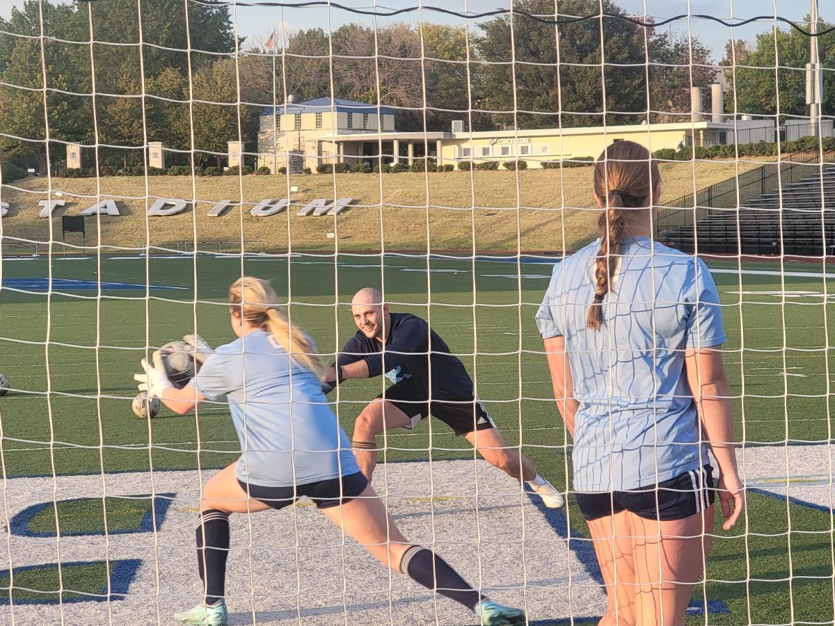 Walker Farrar, goalkeeper coach, running a warm-up drill before practice. Field players and goalkeepers are separated to get individual attention at practice.