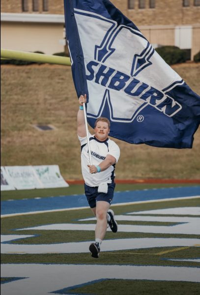 Cole Benzmiller running with the Washburn touchdown flag. This was a prominent job he held on the cheer team. Photo courtesy of Hannah Meier.