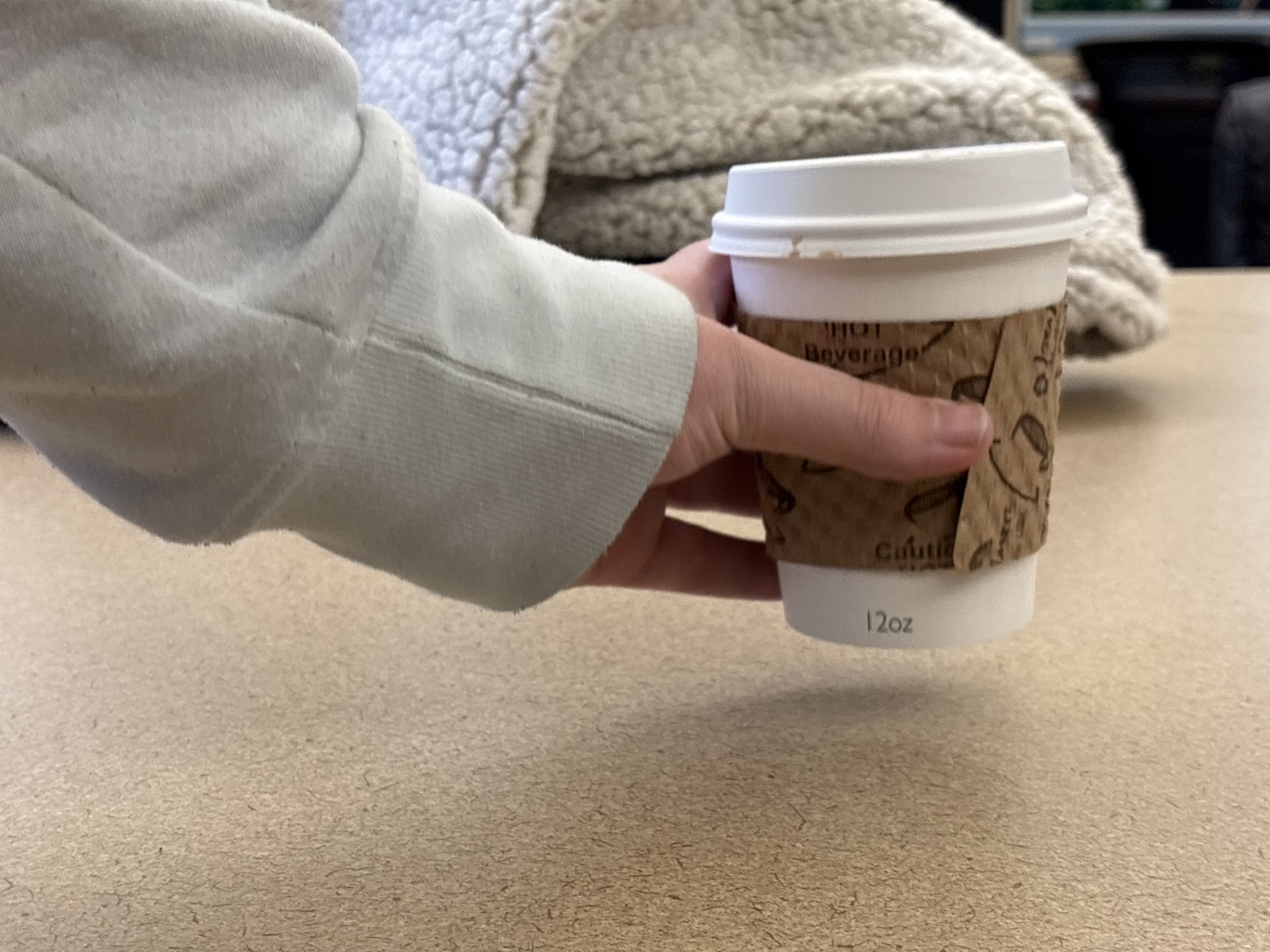 A student grabs a cup of coffee. It was made conveniently in a to-go cup to take to class.