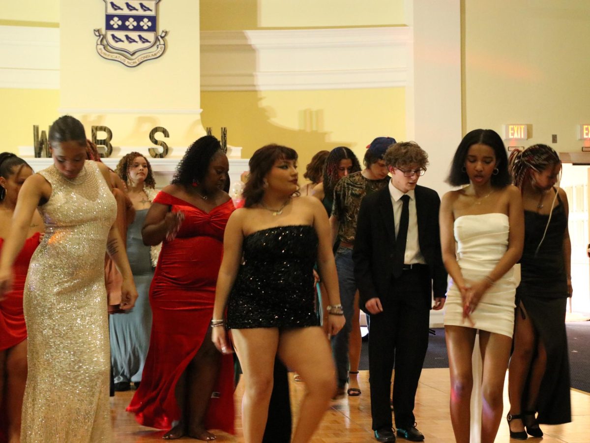 A group of students stand together and showcase their moves. Students attended in fancy and Hollywood party dresses.
