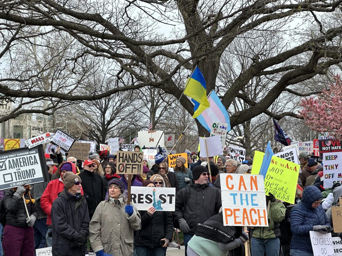 Protesters stand together with the flag of Ukraine and the trans flag raised. 50501 organized and advertised the protest across the state of Kansas.