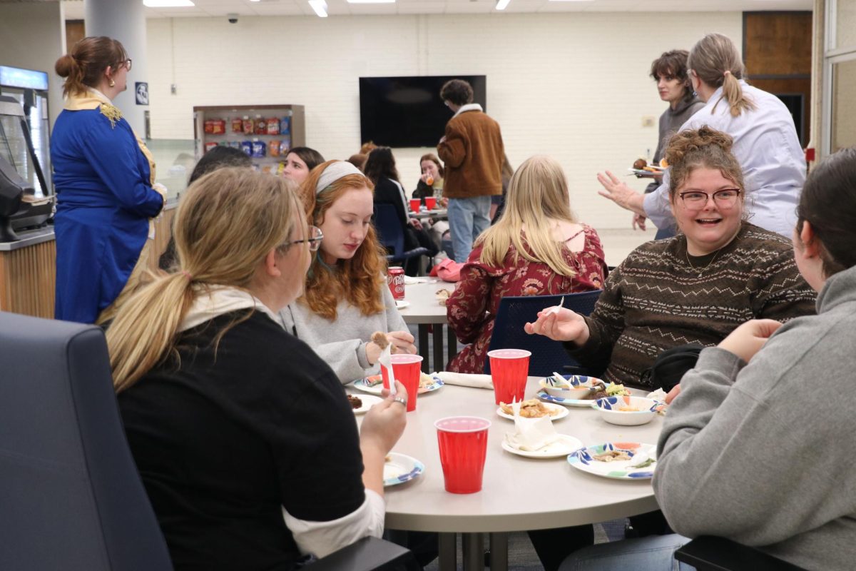 Students gather around tables to eat and talk during the event. The group stayed for food, conversation and a relaxed break before the holiday.
