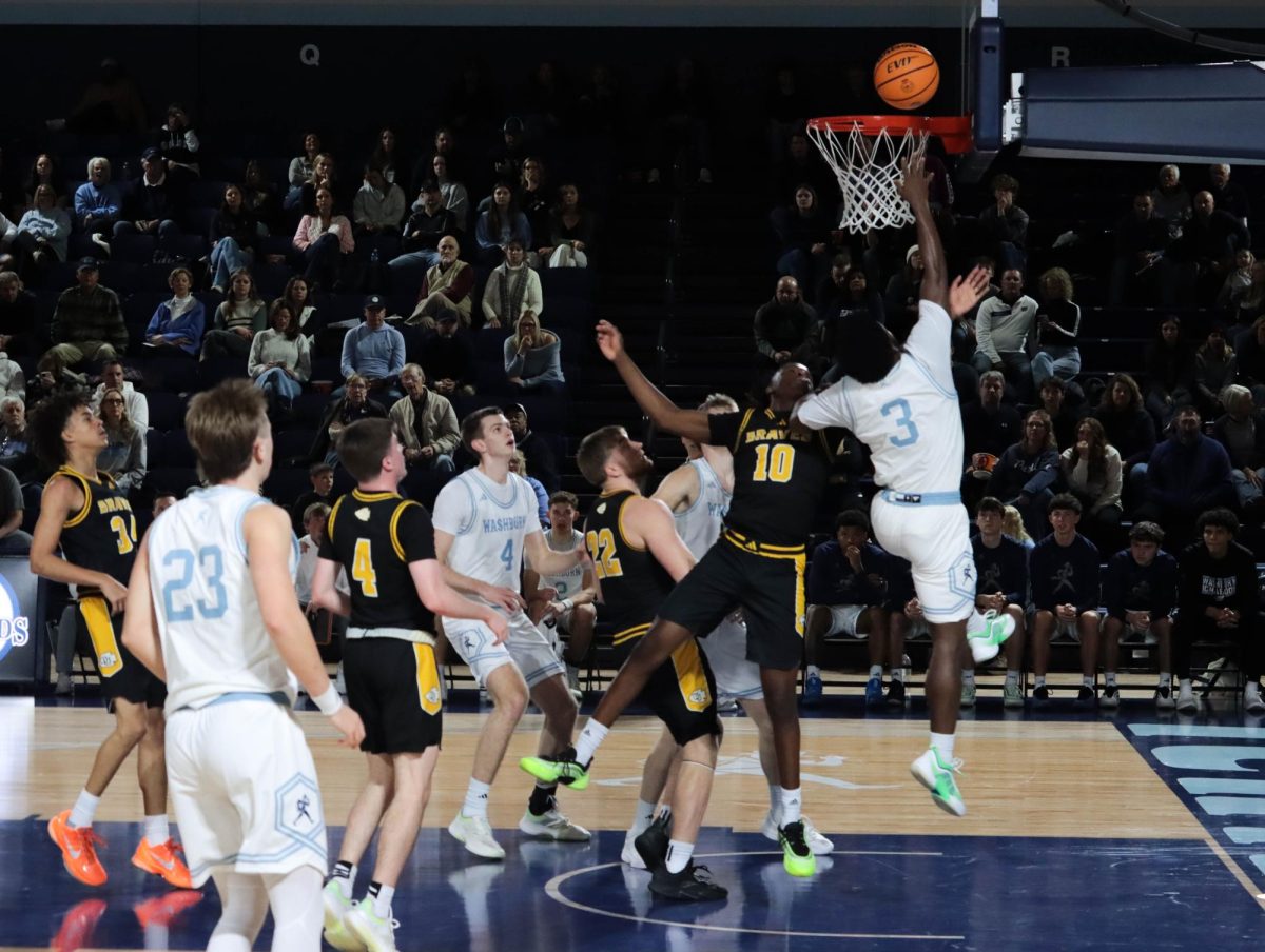 Senior guard Bryson Smith jumps to finish a layup as defenders close in. Earlier, the players were scrambling into position around the lane.
