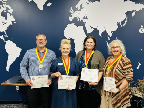 (From left to right) Danny Wade, professor of English and associate provost for faculty development, Tracie Lutz, senior lecturer in education, Melanie Burdick, professor of English and Jeannette Nobo, academic advisor of college of arts and science, display their honor after being inducted into Phi Beta Delta Honor Society for International Scholars. They were inducted in April 2026 in recognition of their contributions to international education, collaboration and global engagement at Washburn University.
